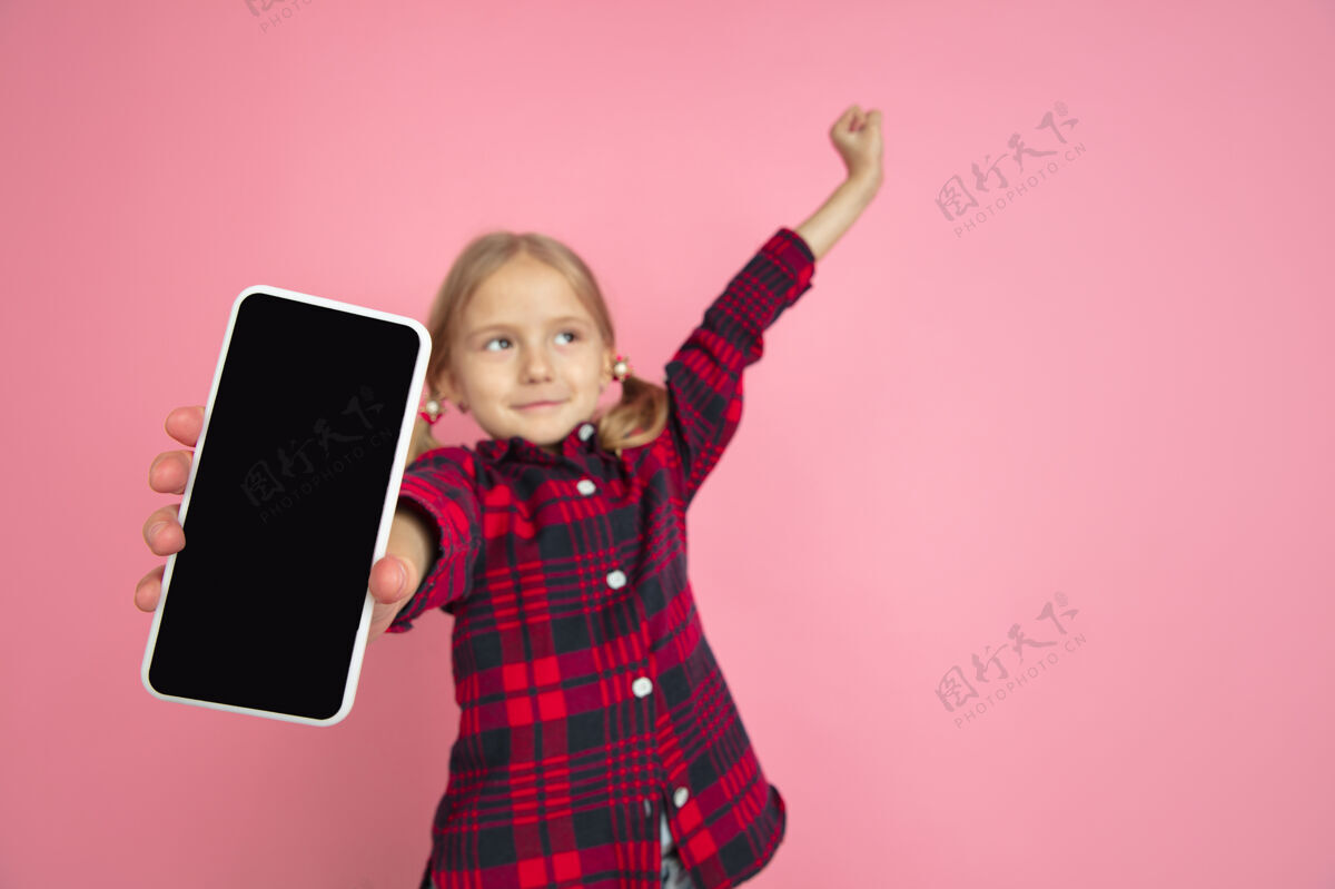 一个显示空白屏幕粉红色墙上高加索小女孩的画像手机复制空间表达