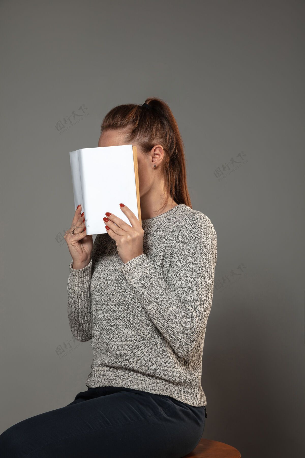 识字世界图书和版权日快乐 读书成为另一个人——在灰色的墙上读书时用书遮住脸的女人女人文学人