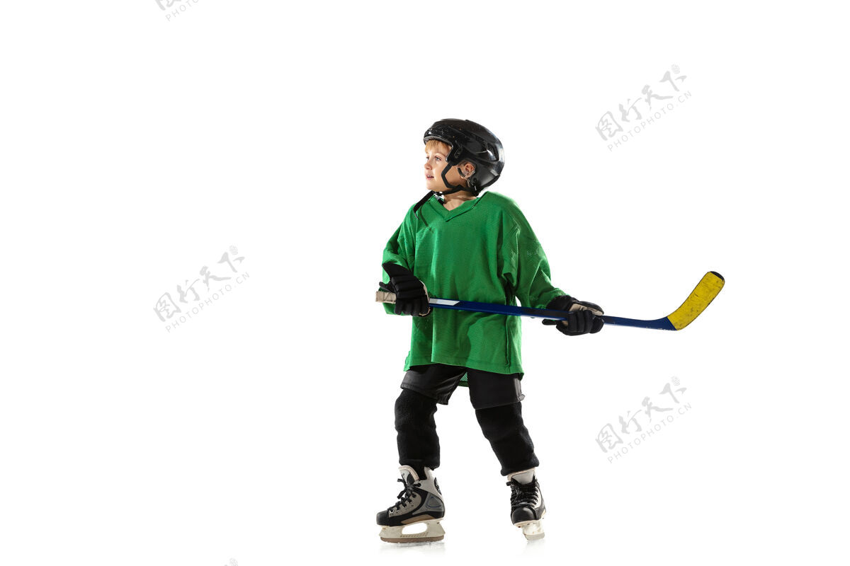 头盔冰球场上的小冰球运动员 白色工作室背景运动员戴着设备和头盔 练习 训练运动的概念 健康的生活方式 运动 运动 动作运动运动男孩