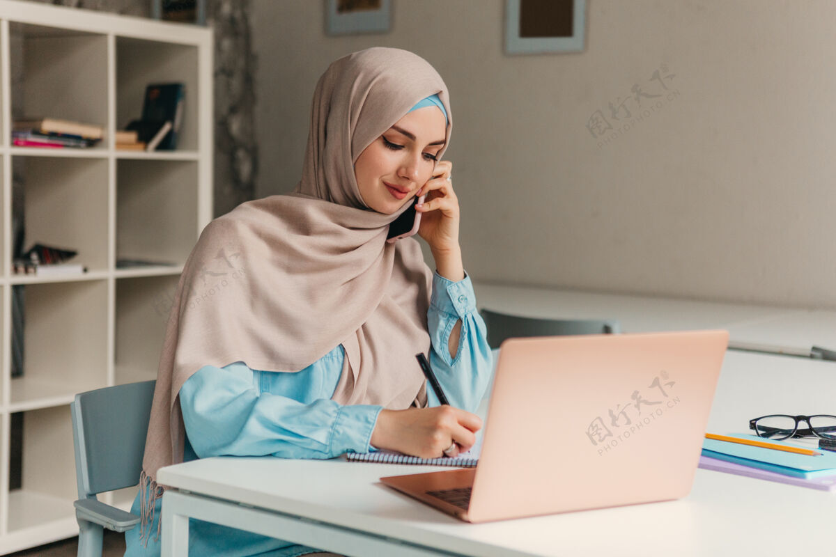 女性年轻漂亮的现代穆斯林妇女戴着头巾在办公室的笔记本电脑上工作 教育在线移动围巾文化