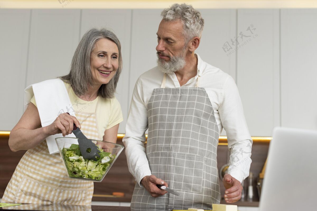 厨房老两口在厨房用笔记本电脑上烹饪课家庭老年人老年人