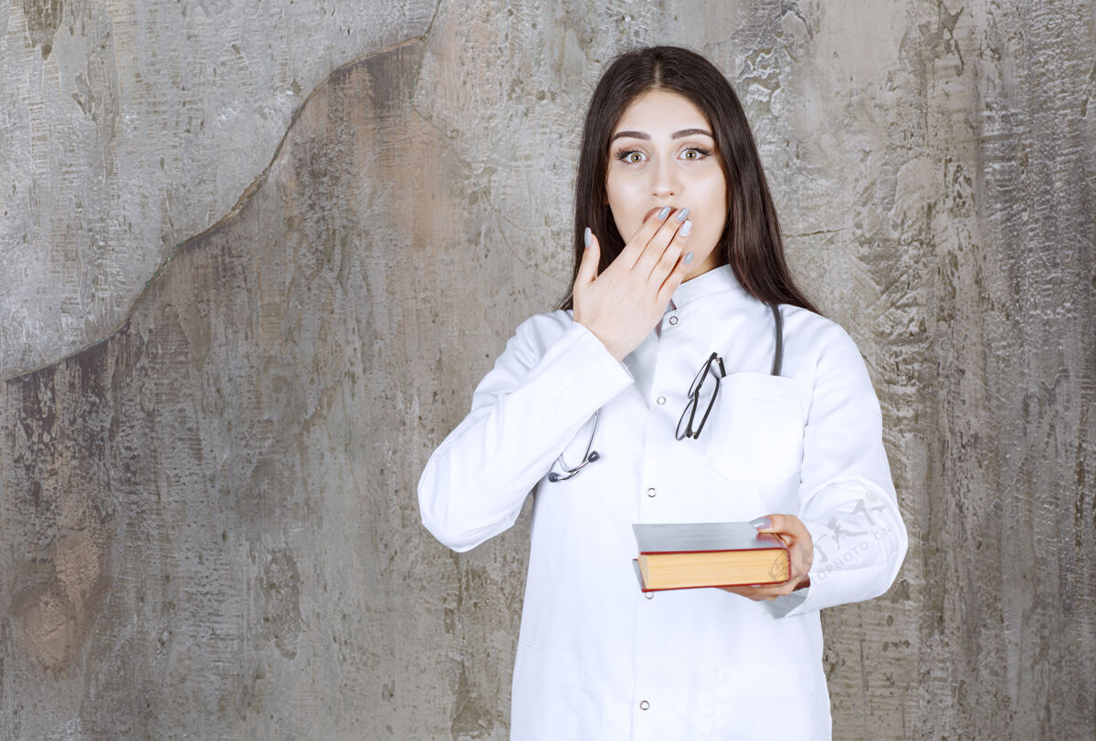 好奇一个心烦意乱的年轻医生 手捂着嘴站在灰墙上工作疾病预防