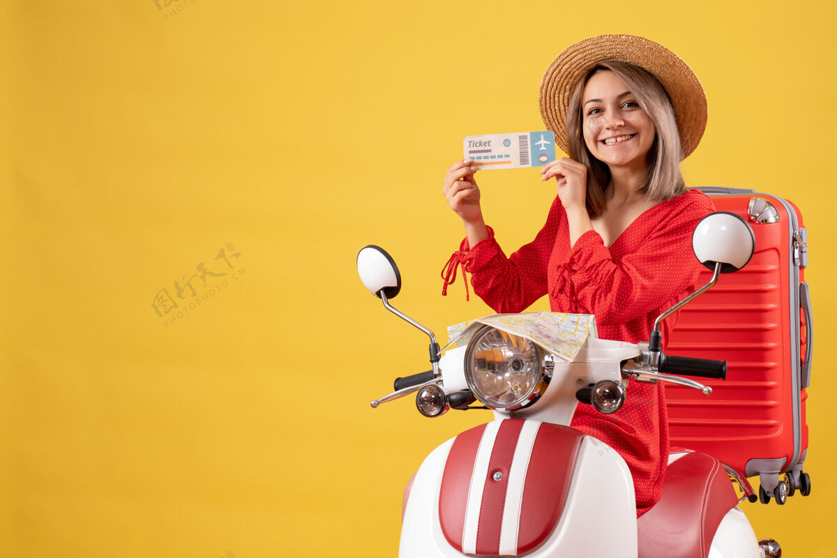 肖像正面图：穿着红色衣服的年轻女士 骑着轻便摩托车 带着红色手提箱 手里拿着车票成人游客人