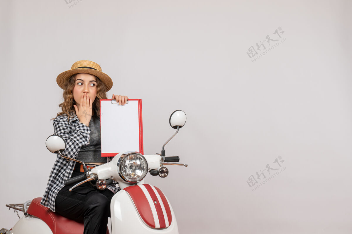 人前视图骑着轻便摩托车的年轻女孩举着剪贴板车辆灰色女人