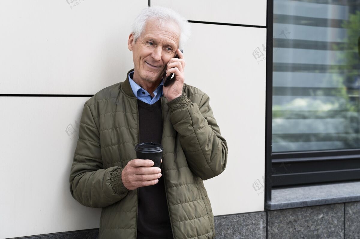 移动笑笑城里的老人一边喝咖啡一边用智能手机说话设备水平老年人