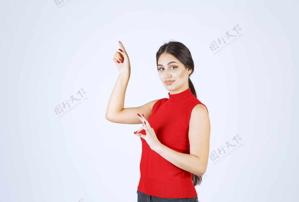 享受穿红衬衫的女孩显示出积极的手势服装成人休闲