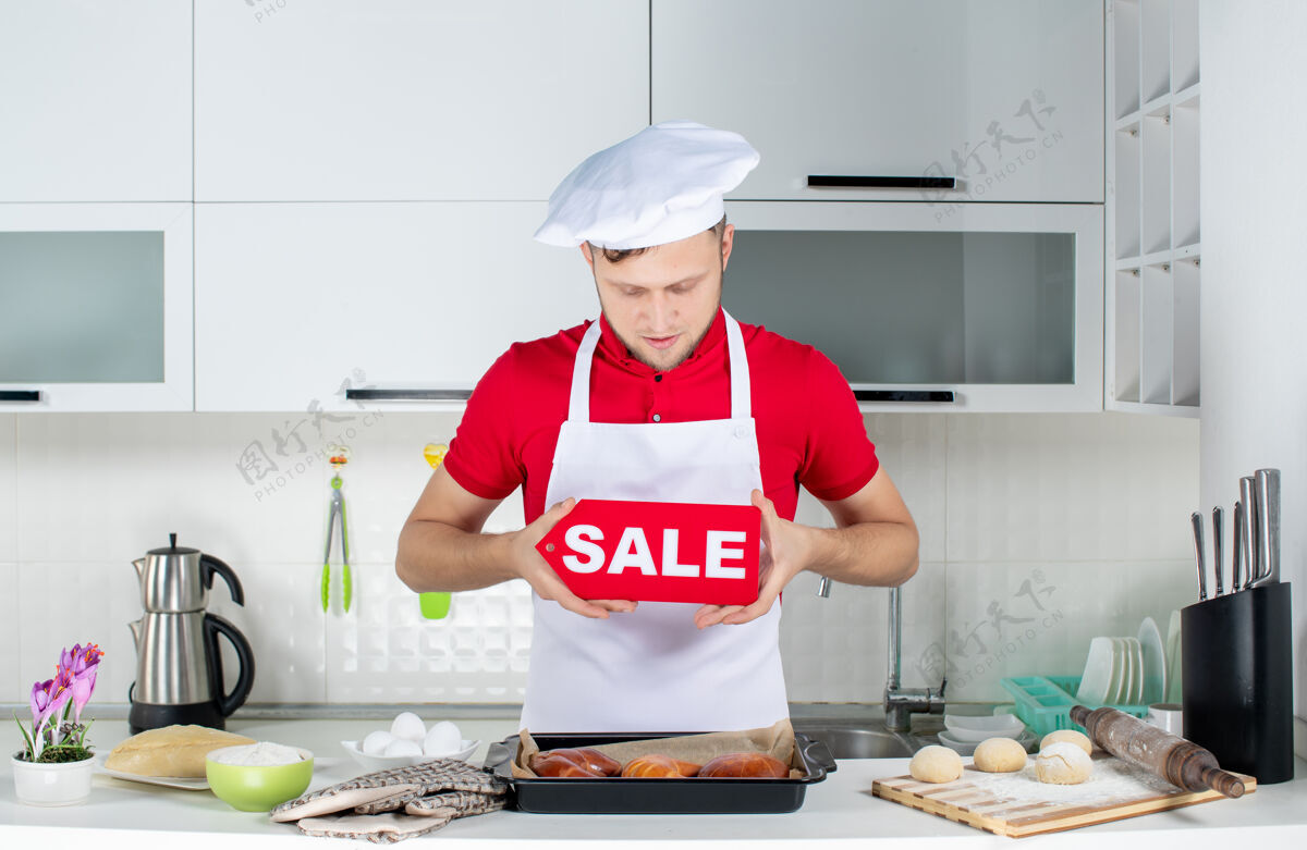 男人白色厨房里年轻集中的男厨师展示销售标志的俯视图帽子男性人