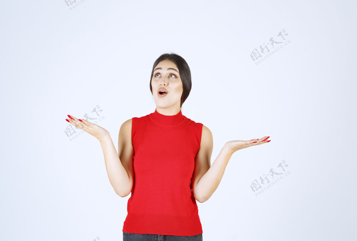 女性穿红衬衫的女孩在她张开的手上展示着什么年轻人工人服装