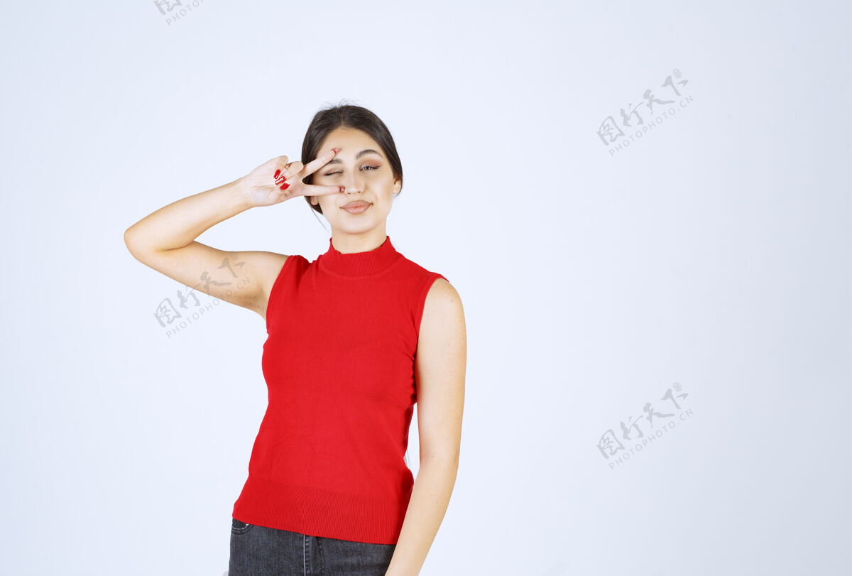 模特穿红衬衫的女孩透过手指看女人职员雇员