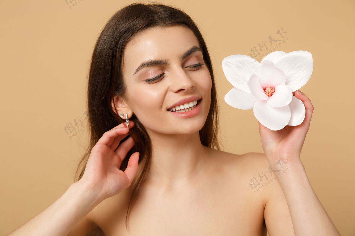 女性特写黑发半裸女人完美的皮肤 裸妆隔离在米色粉彩墙上室内清除化妆品