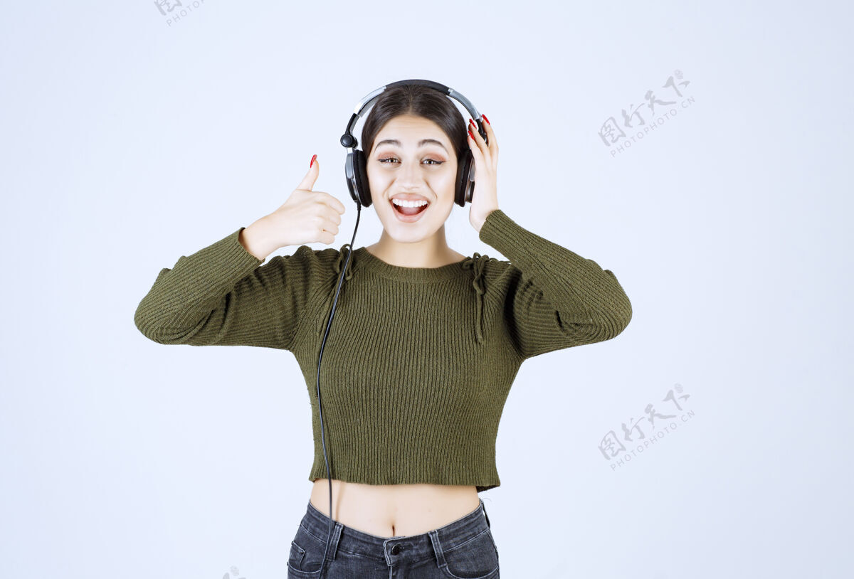 音乐戴着耳机听音乐竖起大拇指的年轻女孩的画像人耳机表达
