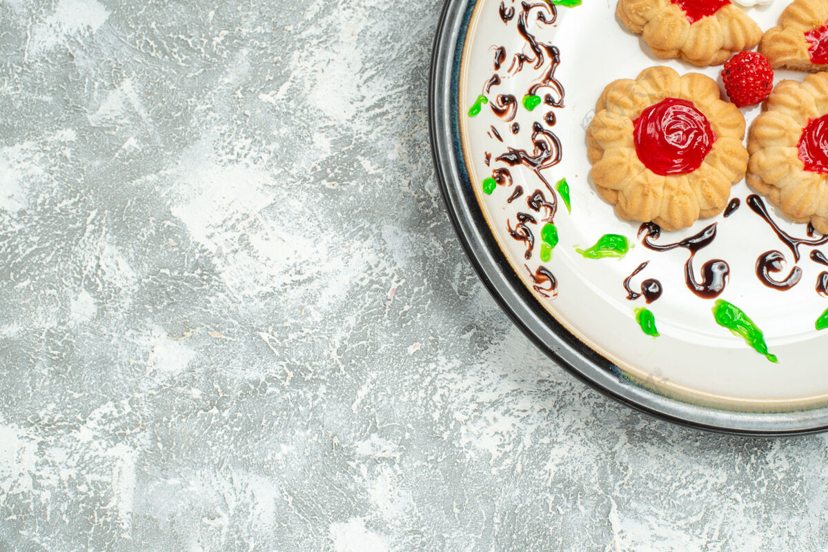 美味饼干顶视图美味饼干与红色果冻内板上的白色背景糖饼干蛋糕饼干甜茶视图饼干盘子