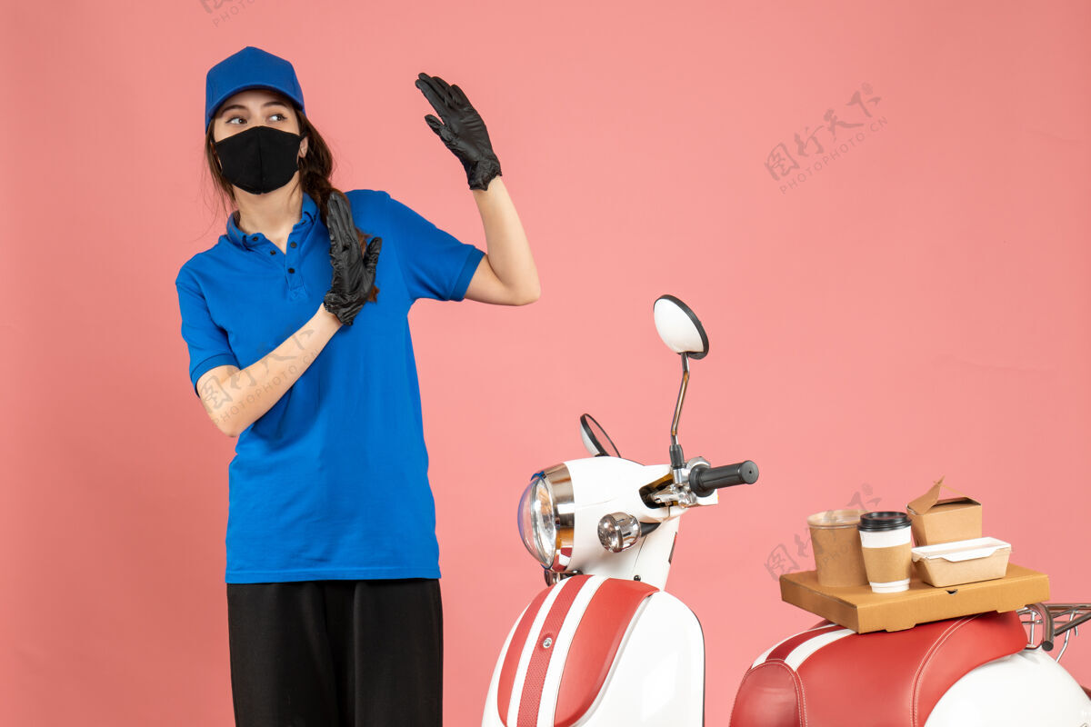 站俯视图中 戴着医用面罩的受惊信使女孩站在摩托车旁 粉色背景上有咖啡蛋糕桃咖啡医学