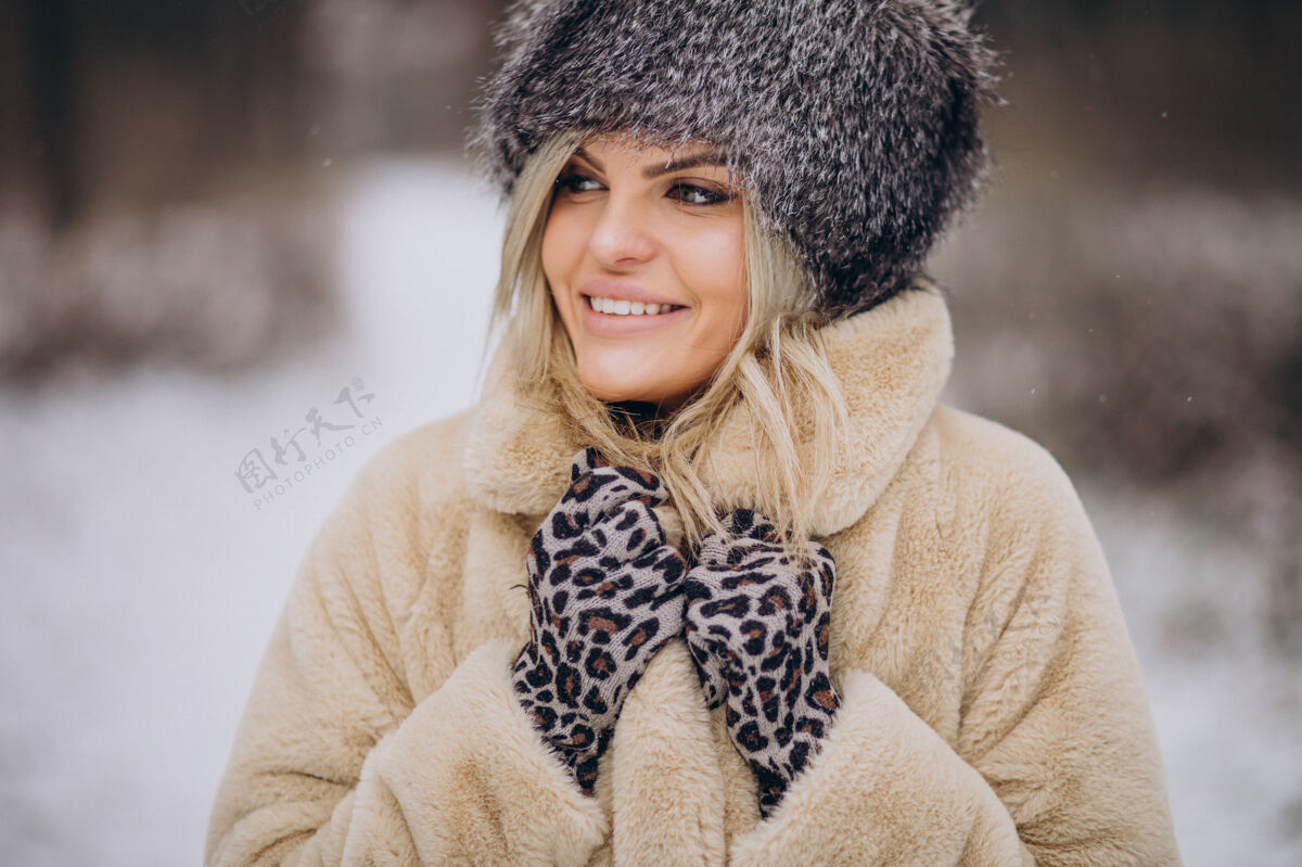 温暖的衣服美丽的女人在满是雪的公园里散步女性波西米亚微笑