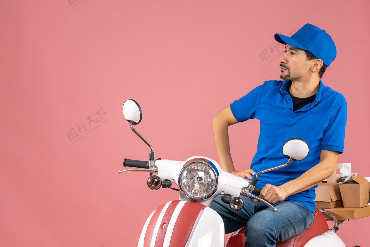 桃正面图贴心的送货员戴着帽子坐在粉彩桃色背景上的滑板车上前面车辆坐