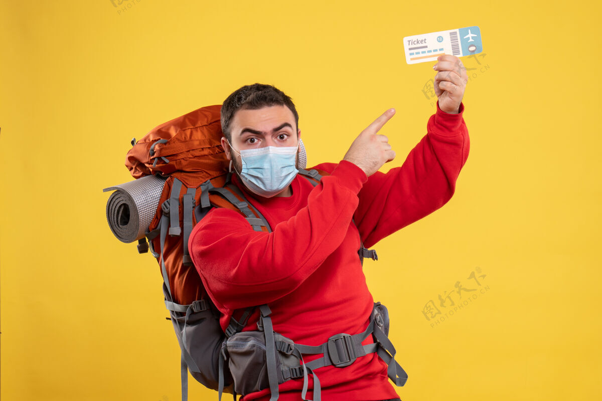 男人年轻自信的旅行者 戴着医用口罩 背着背包 手里拿着黄色的机票医疗成人黄