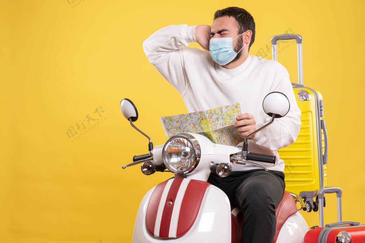 医疗旅行的概念与情绪化的家伙在医疗面具坐在摩托车上黄色手提箱上男头痛人