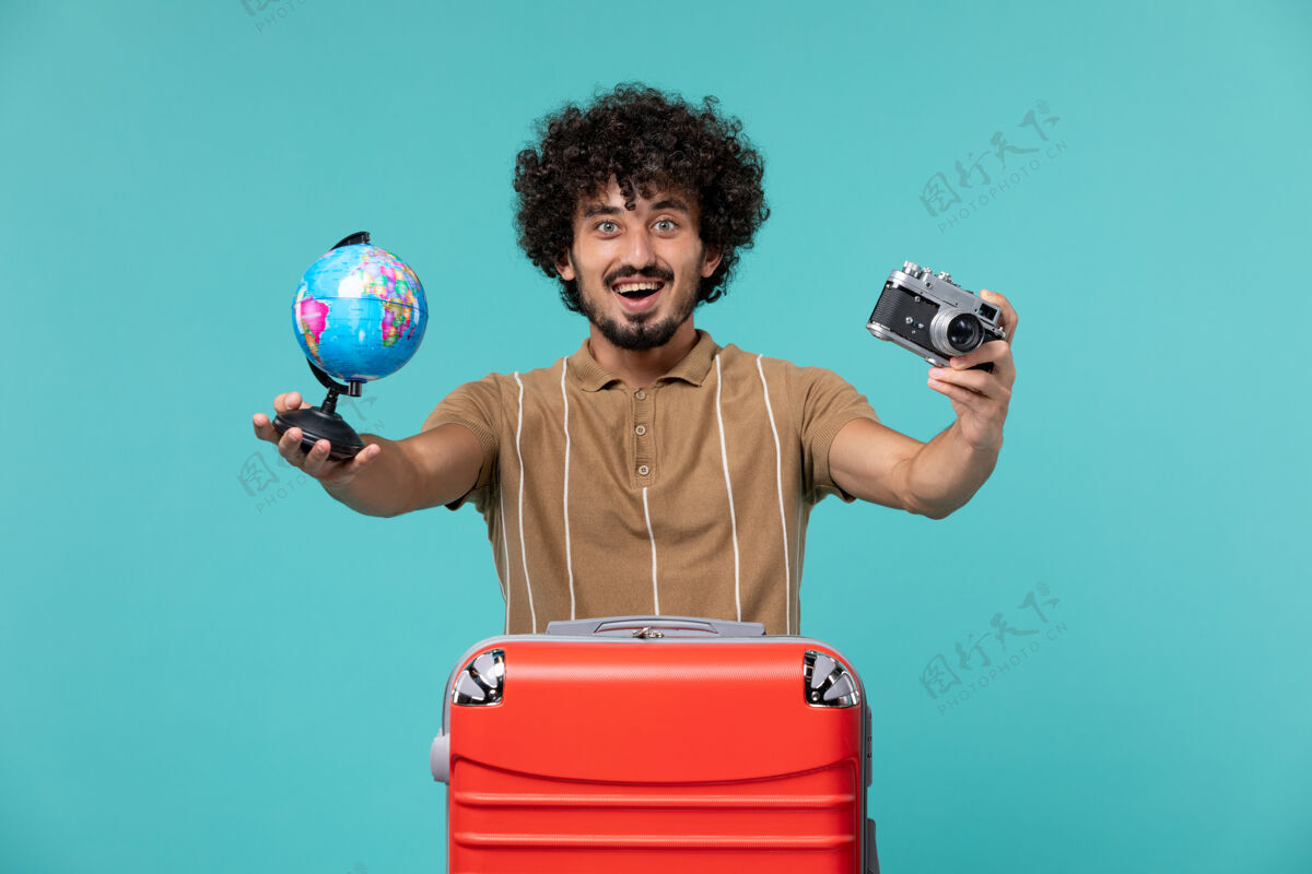 成人度假的男人拿着浅蓝色的小地球仪和照相机旅行地球仪假期