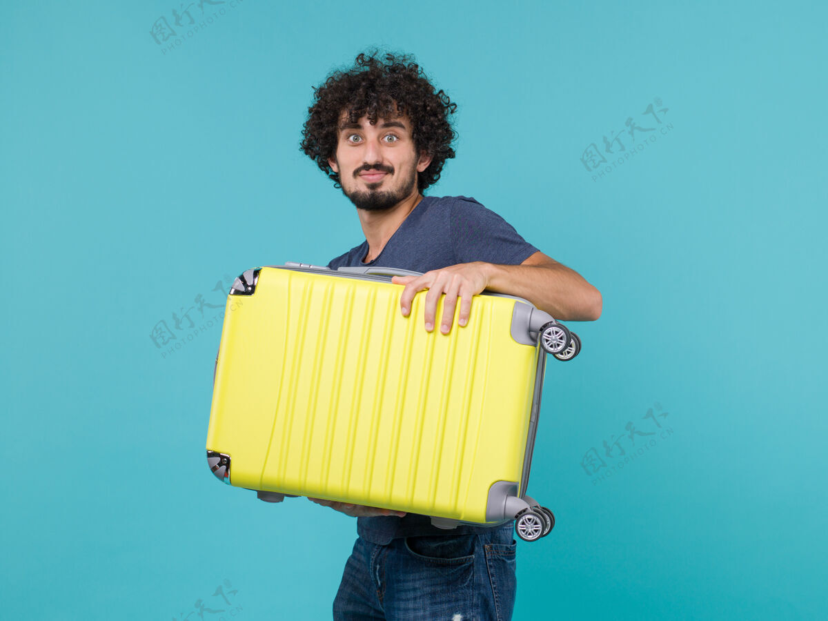 成人度假的男人拿着蓝色的大黄色手提箱假期旅行人