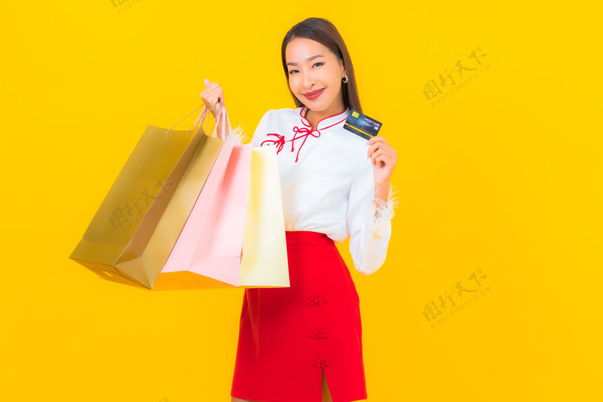 泰国一位年轻漂亮的亚洲女士 手拿购物袋 信用卡 黄色消费主义肖像在线