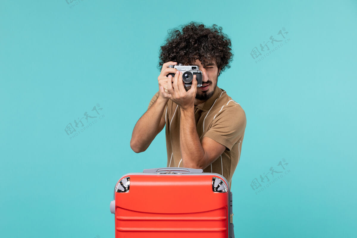 手提箱带着红色手提箱的度假男人用蓝色的相机拍照集装箱旅行成人