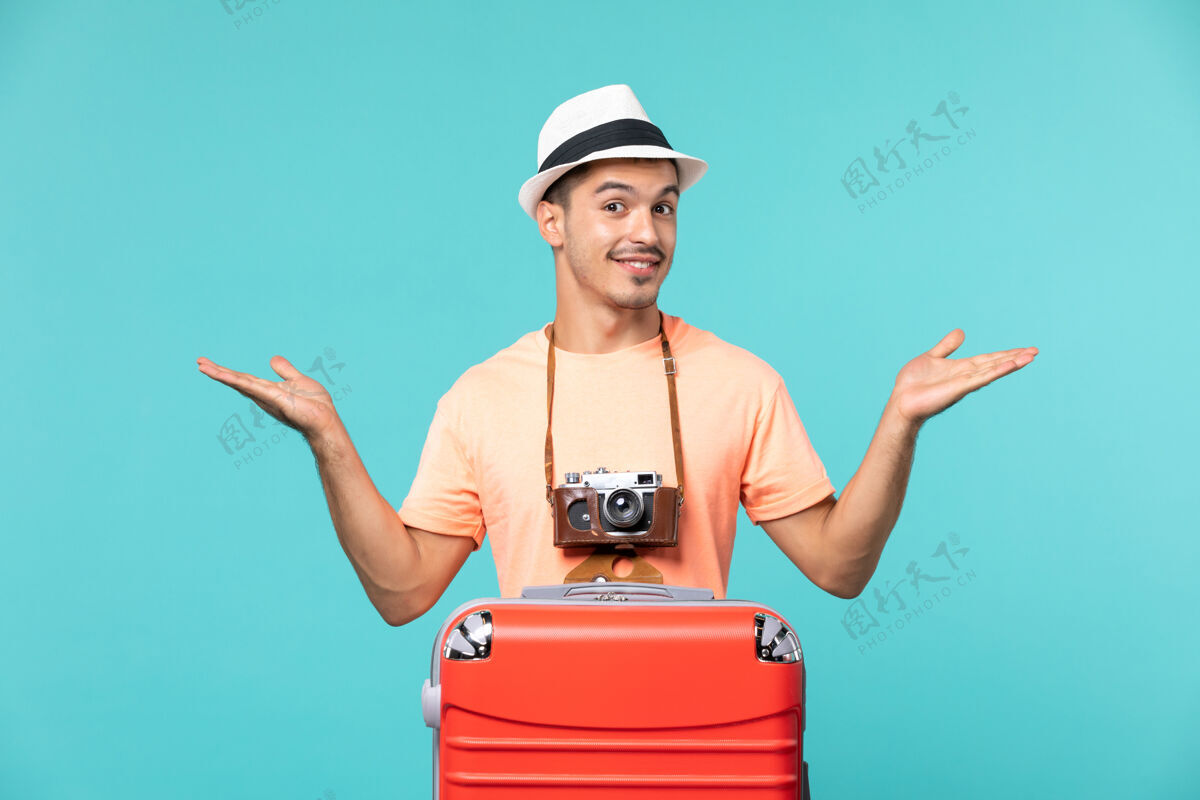 红带着红色手提箱和蓝色相机的度假男人人航程假期