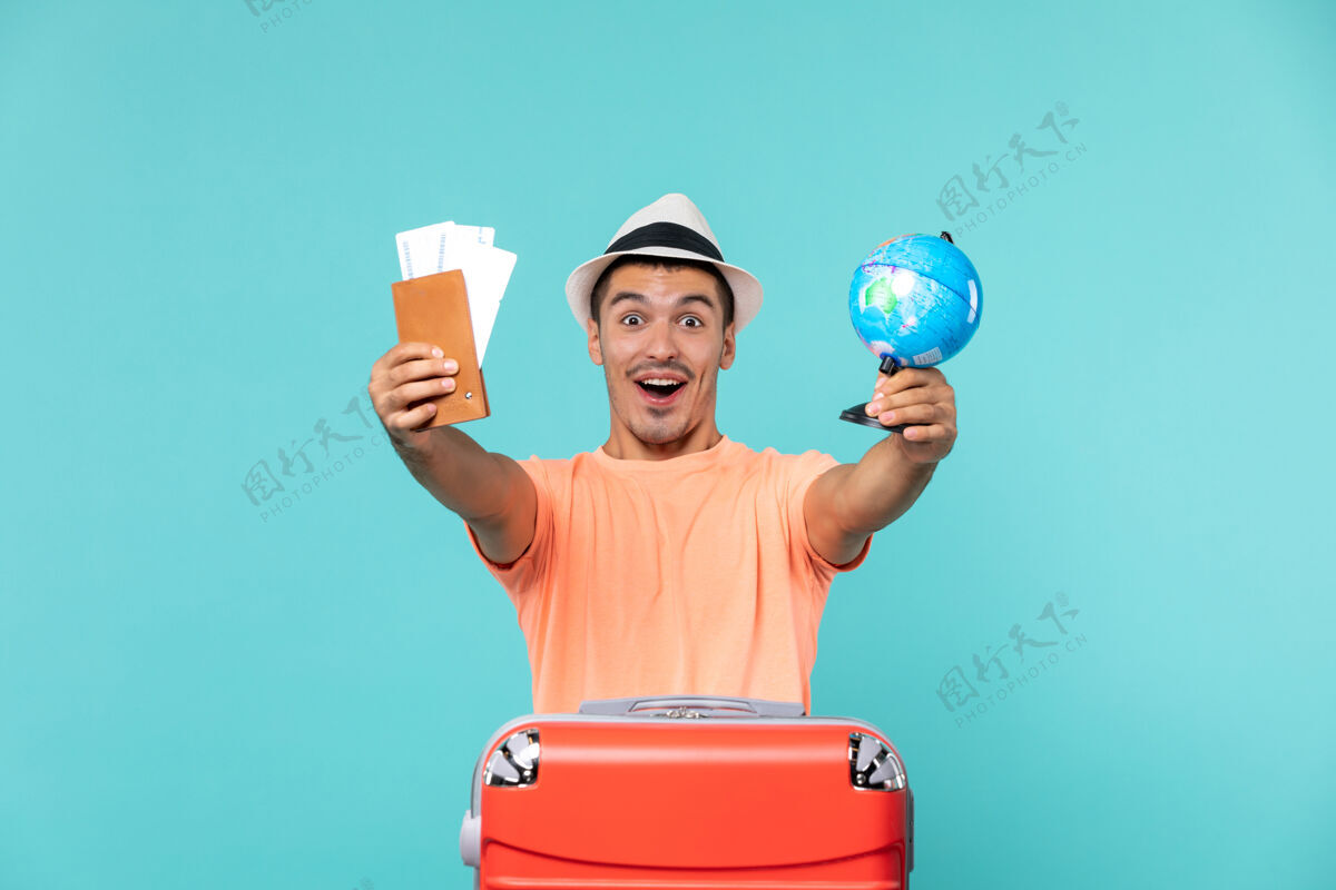 举行正面图男性在度假时拿着小地球仪和门票兴奋的蓝色兴奋假期地球仪