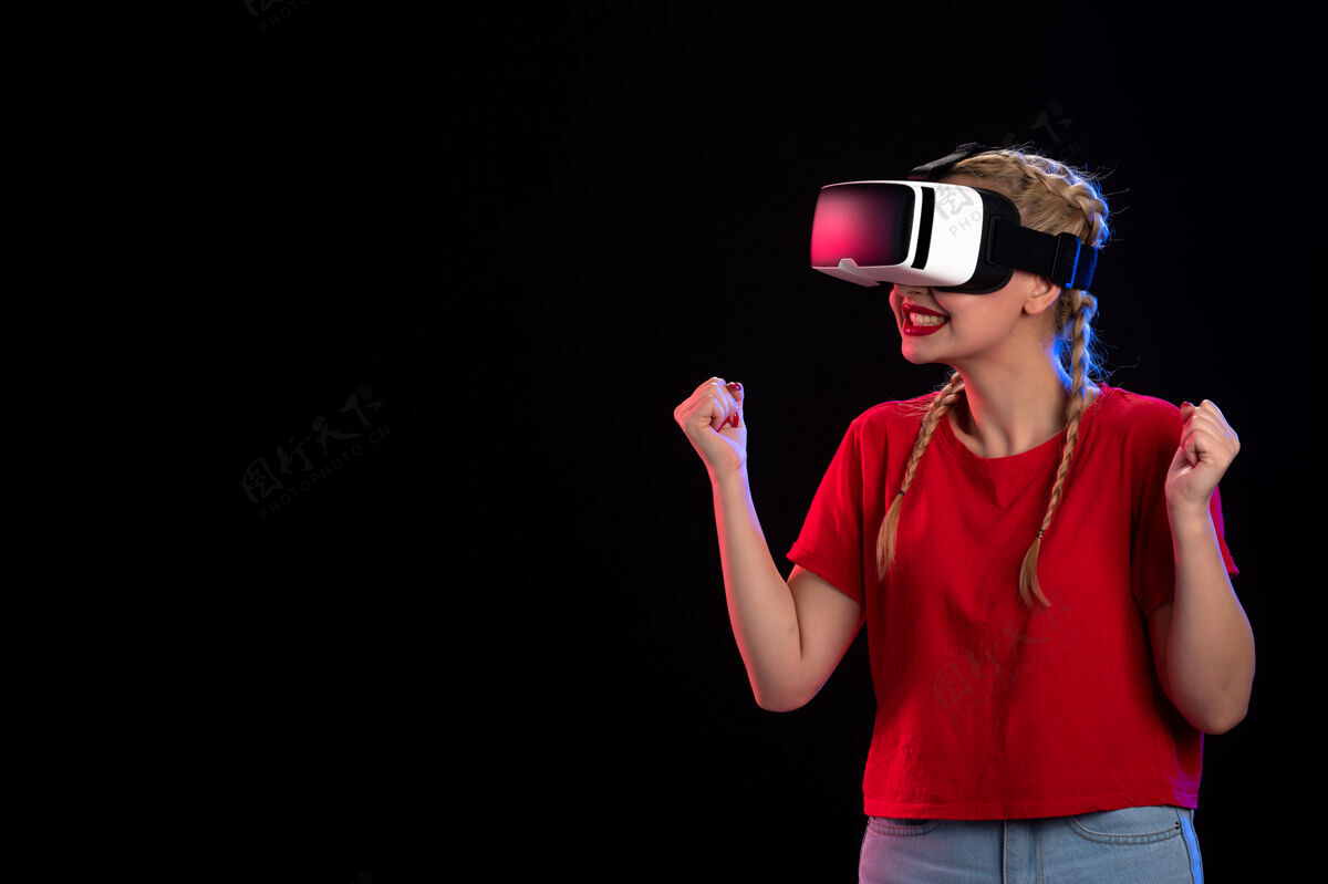 正面年轻女性在黑暗的墙上玩虚拟现实的正面图虚拟现实年轻女性人物