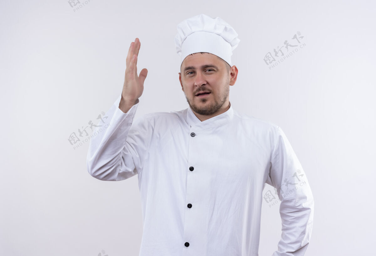 烹饪自信的年轻帅哥厨师身着厨师制服 举起的手孤立在白墙上年轻自信手