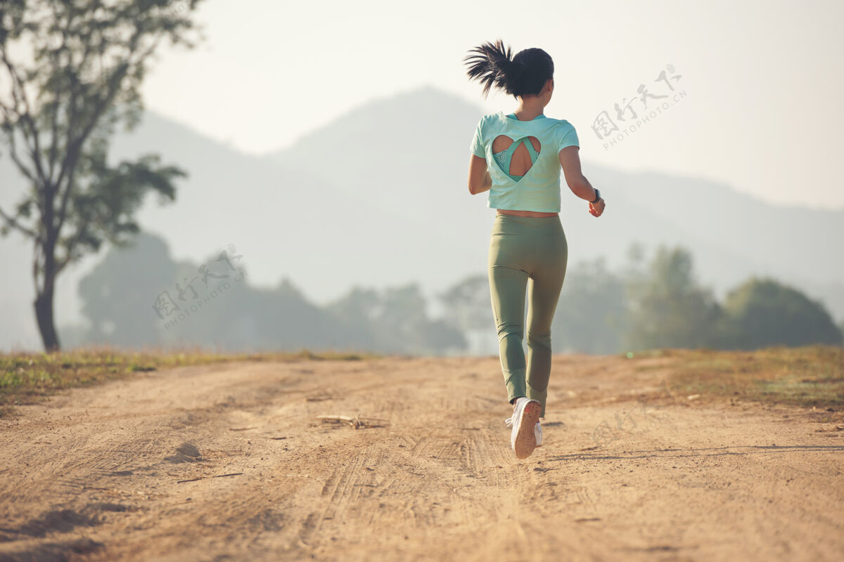 运动年轻女士享受着健康的生活方式 一边在乡村公路上慢跑 一边在户外锻炼和健身年轻女士在日落时分在乡村公路上跑步健康生活方式女性速度