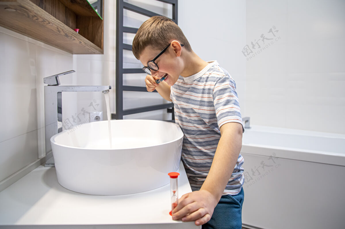 沙漏一个可爱的小男孩刷牙 用沙漏计时童年孩子小时