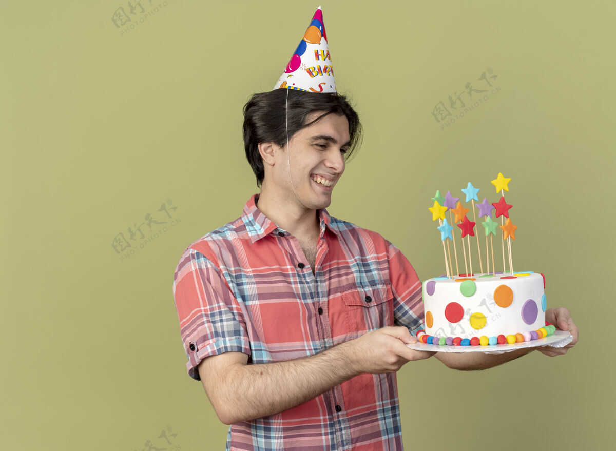 男人一个戴着生日帽 面带微笑的白人帅哥拿着生日蛋糕看蛋糕复制微笑