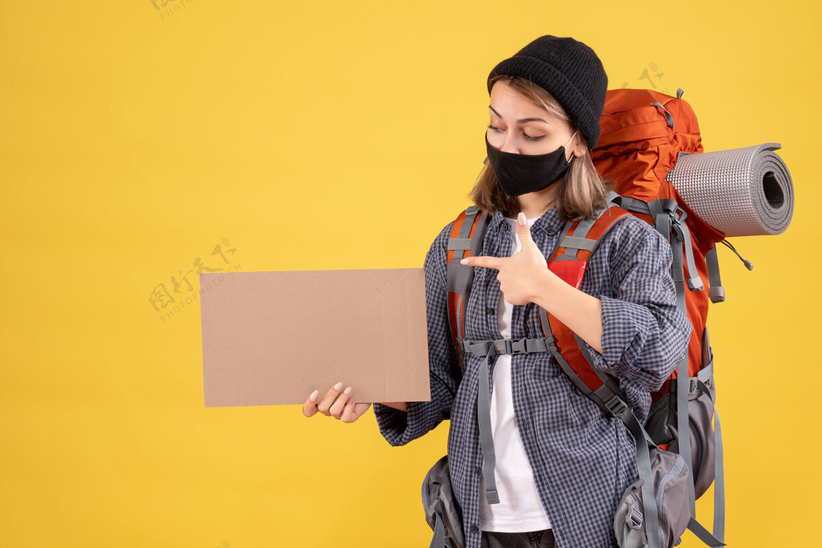 女孩旅行者带着黑色面具的旅行女孩指着纸板纸板表情成人