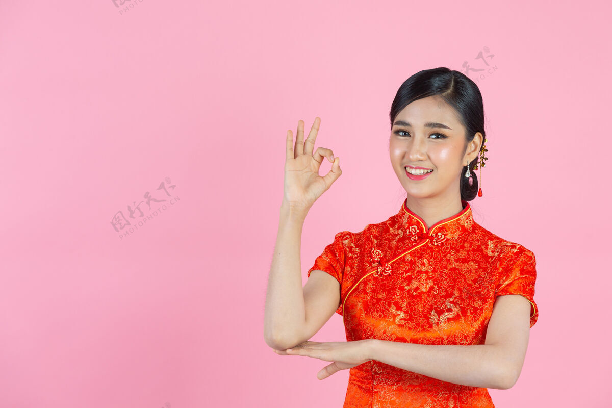 文化美丽的亚洲女人快乐的微笑 在中国新年的粉红色背景上向你展示一些东西东方人女孩女人