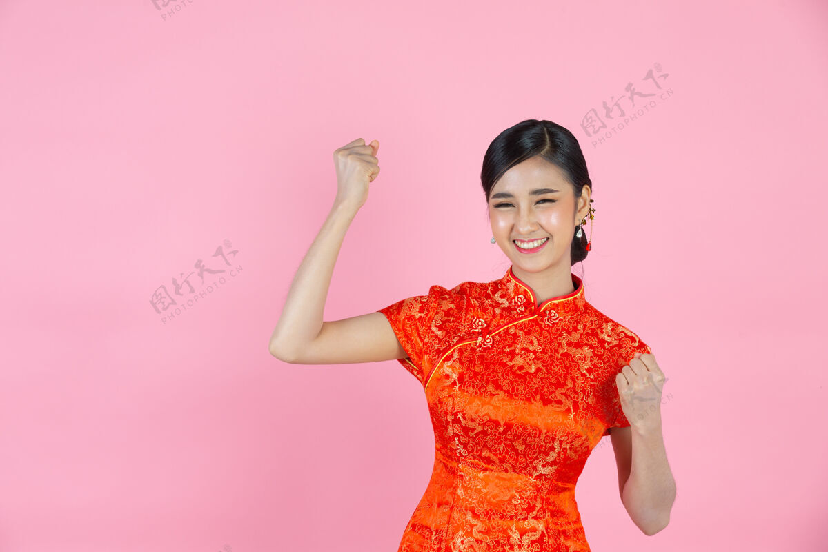 欢呼美丽的亚洲女人在粉色背景的中国新年里快乐的微笑和兴奋空白微笑中国