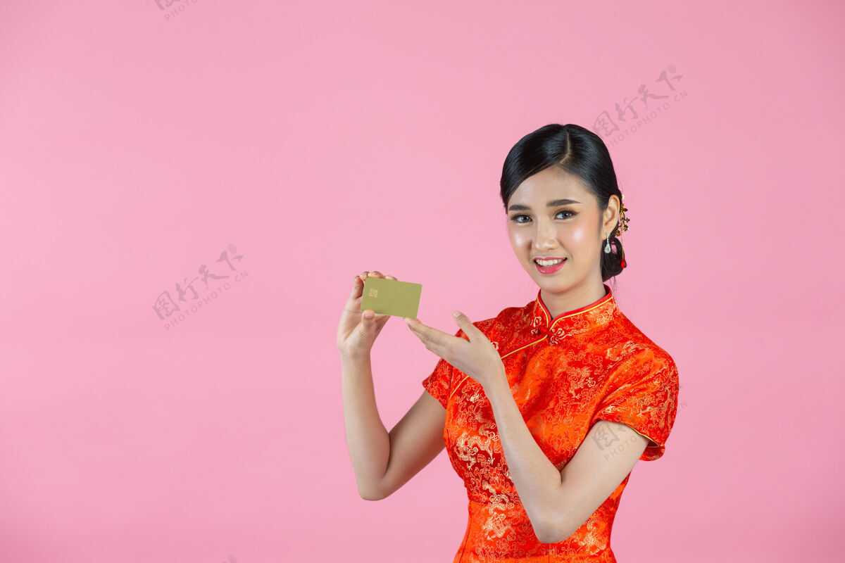 问候语美丽的亚洲女人开心的微笑 在粉色背景上展示中国新年的信用卡女孩信用卡空白