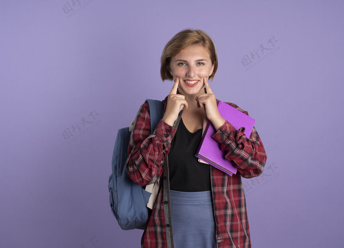 手指微笑的年轻斯拉夫学生女孩背着书包 手指拿着书和笔记本 保持微笑微笑笔记本复制