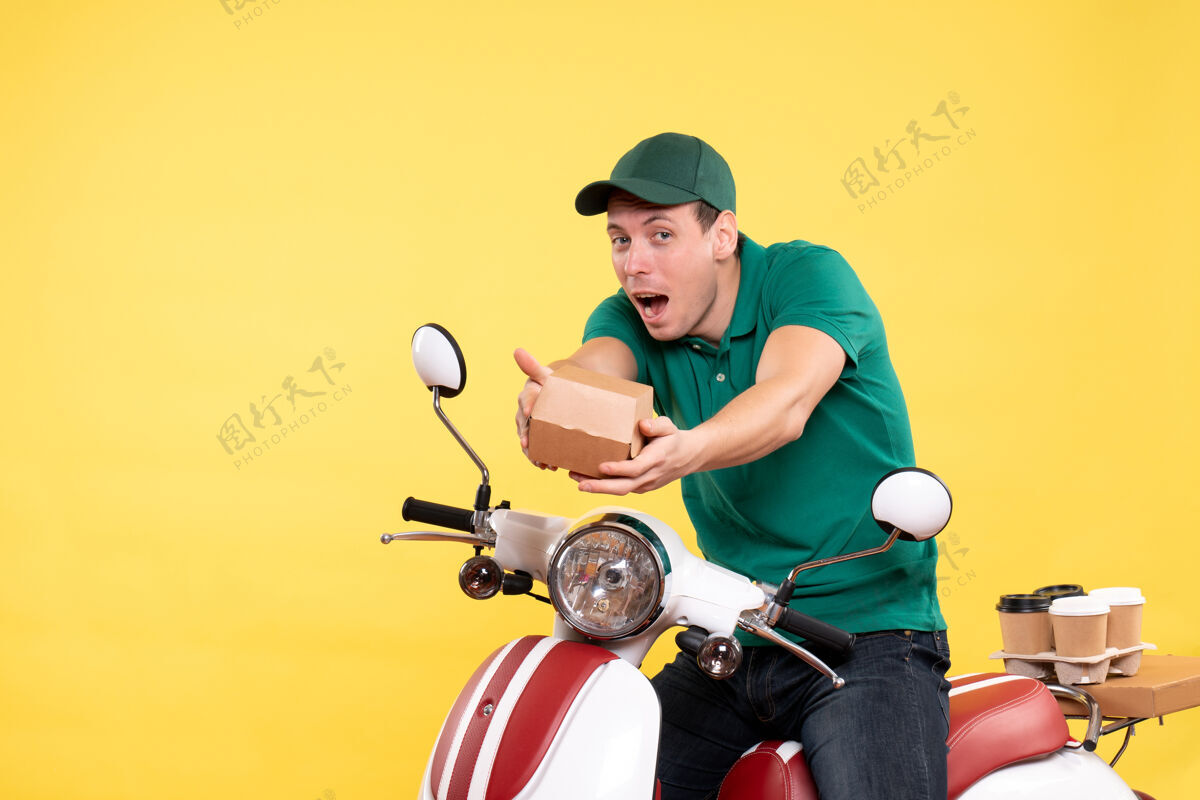 食品正面图身穿制服的年轻男快递员拿着黄色的小食品包摩托车工作快餐