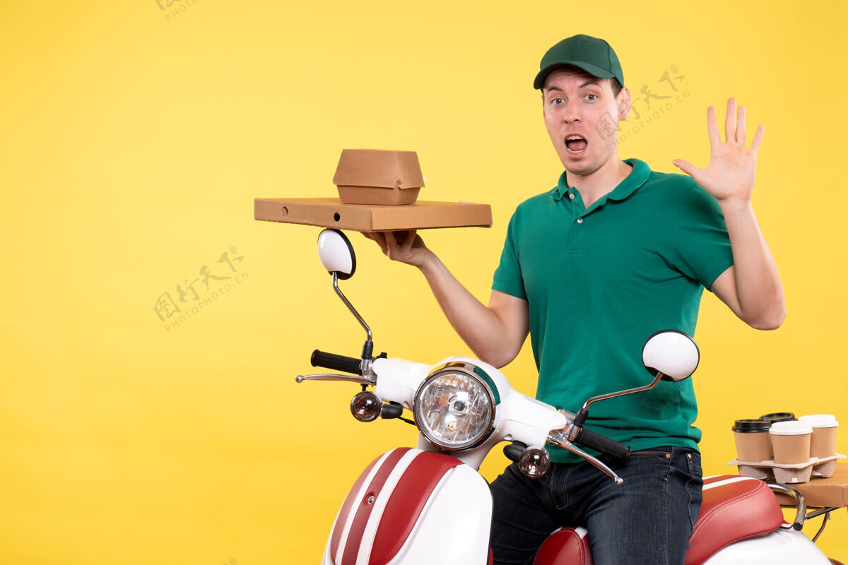摩托车正面图身着制服的年轻男性快递员手持黄色食品包装食品制服年轻男性信使