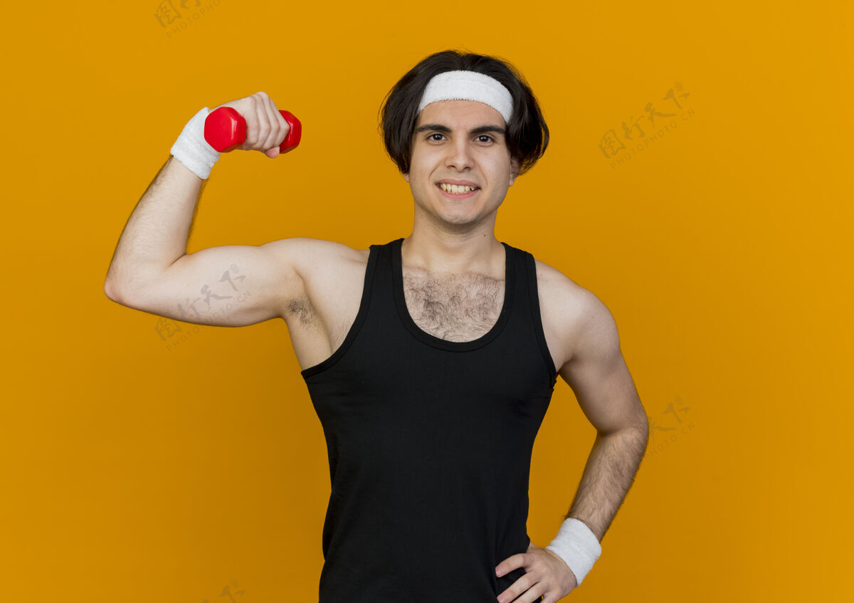 运动装穿着运动服 头戴头巾 手举哑铃 微笑自信地站着做运动的年轻人橙色男人头带