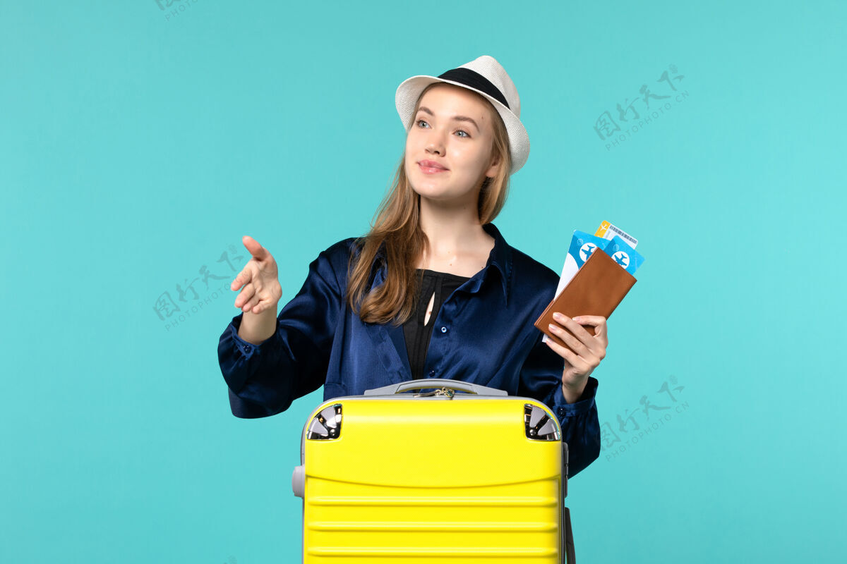 航行前视图年轻女子拿着她的票 准备在蓝色背景上迎接某人旅行航程飞机海上度假旅行举行旅行人