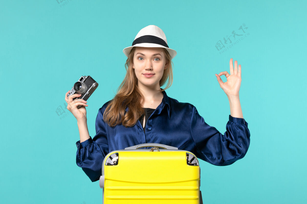 微笑前视图年轻女子手持相机 微笑着在蓝色背景下的女子旅程航行飞机海肖像手持旅程