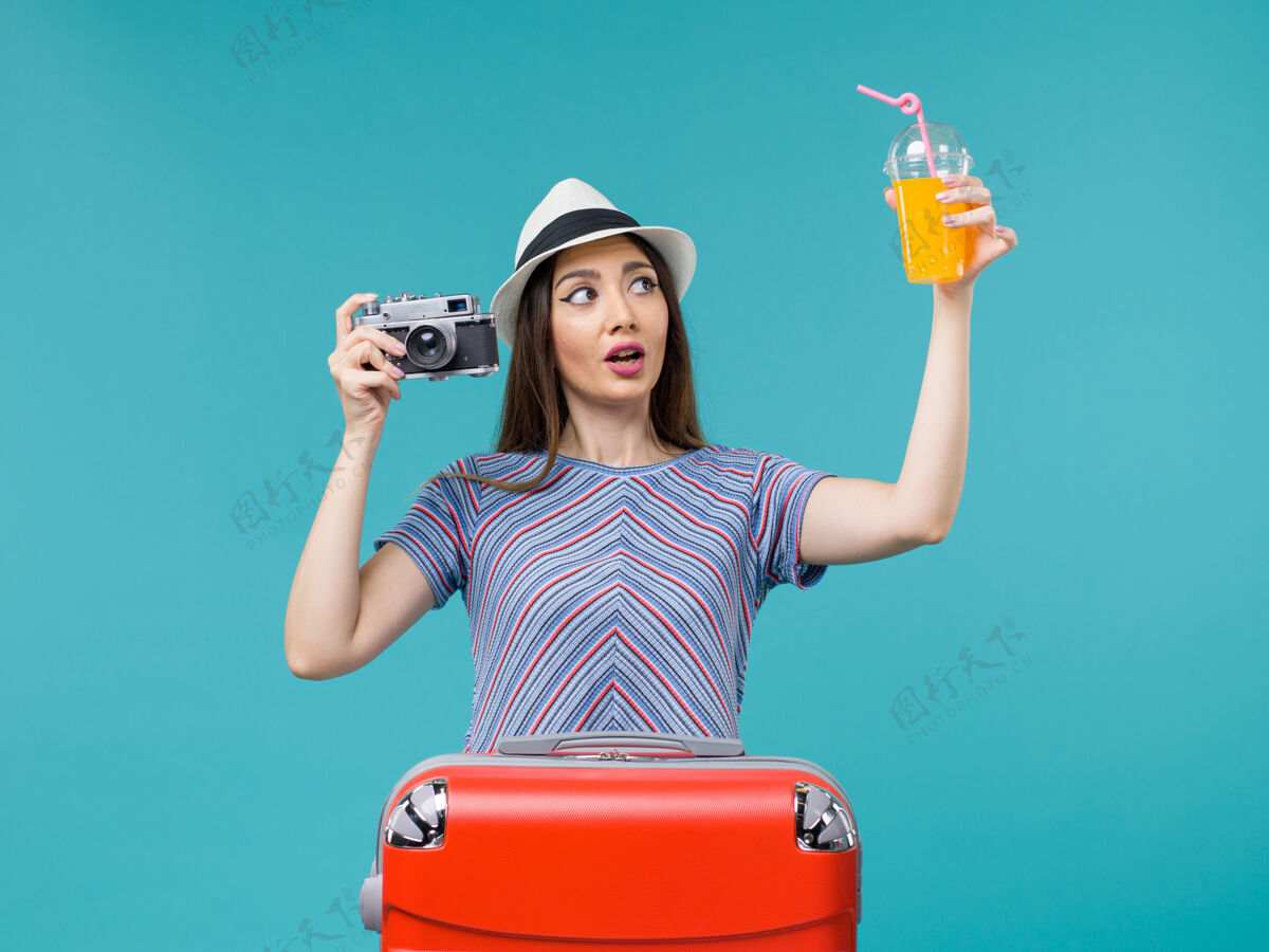 肖像前景度假中的女人拿着果汁和相机在蓝色的背景海上航行避暑果汁航行美丽