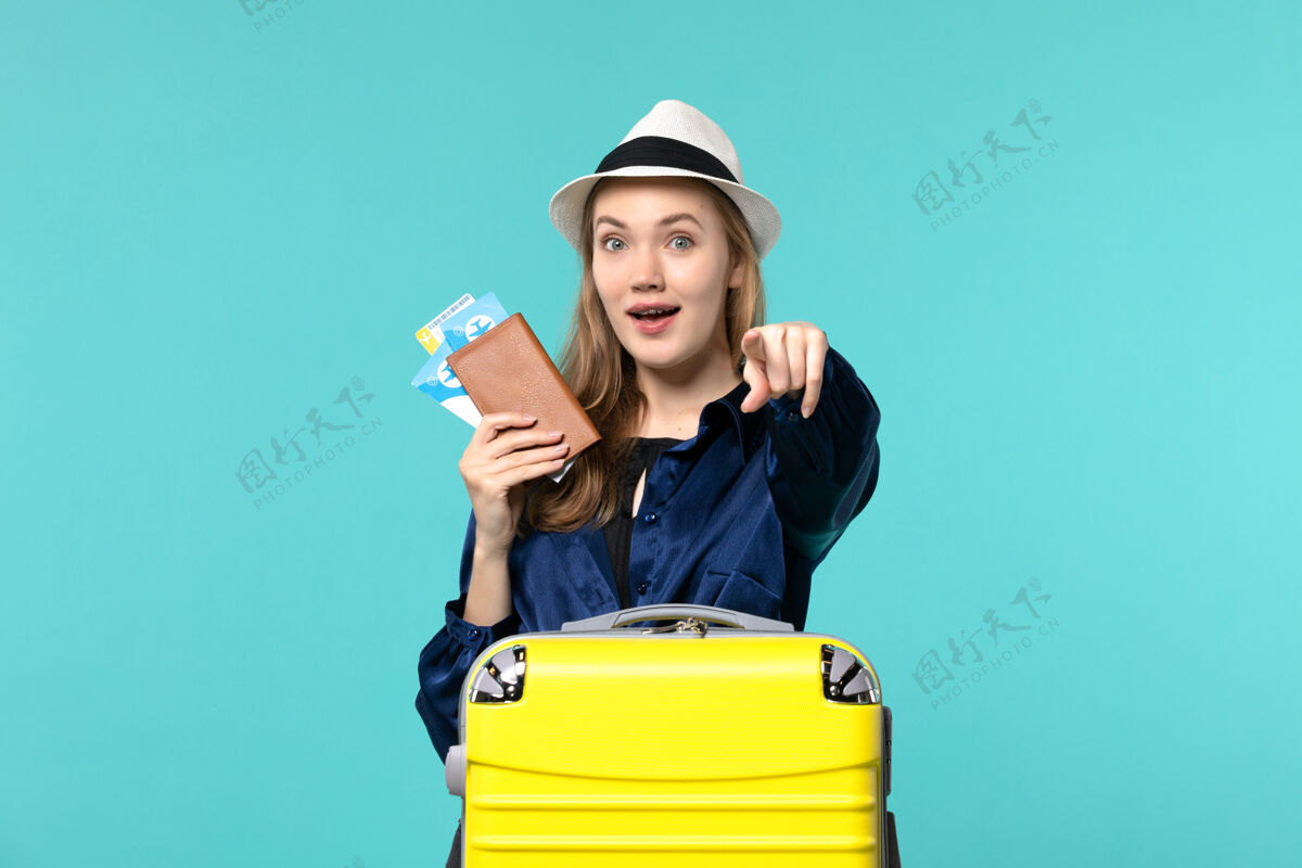 成人前视图年轻女子拿着机票 准备在蓝色背景下旅行海上度假旅行飞机旅行等待年轻女子旅行