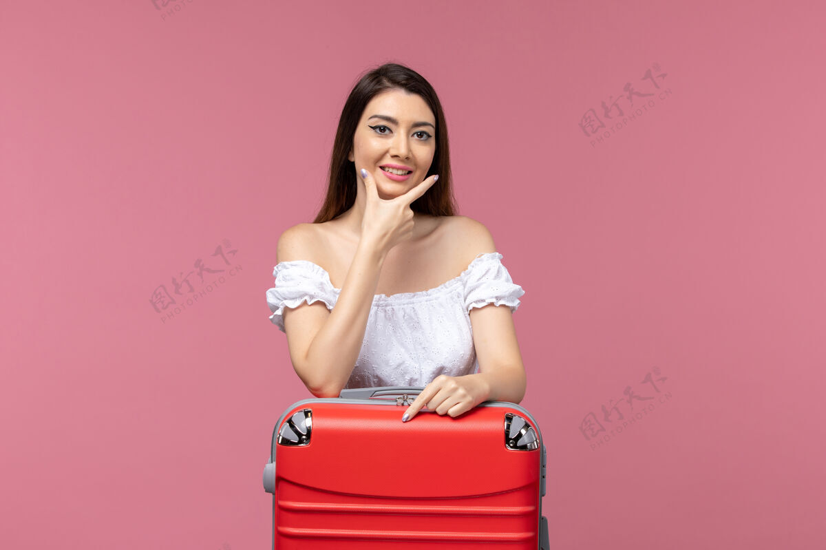 包正面图：年轻女子带着她的红色书包在粉色书桌上准备度假旅行海上旅行妇女出国度假旅行黑发美女