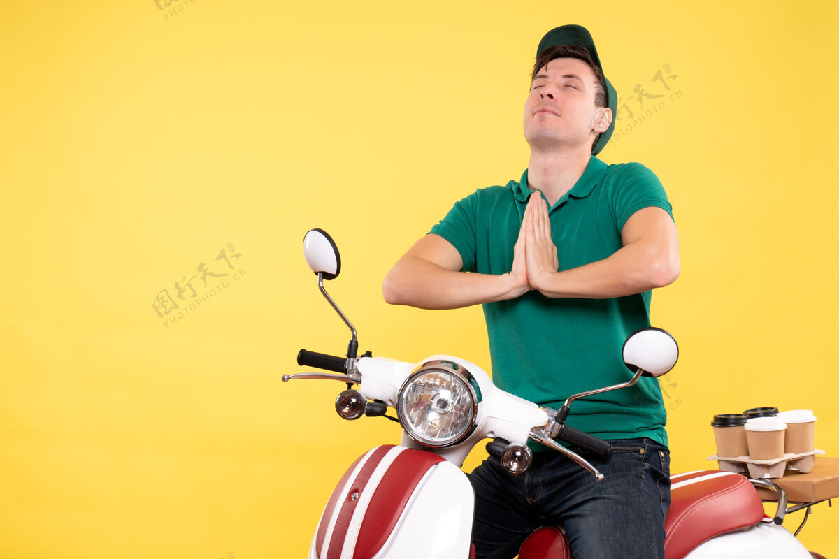 活跃正面图：穿着绿色制服骑着黄色自行车的年轻男信使工人工作比赛