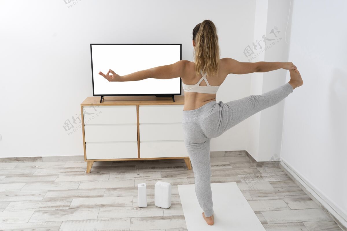 电视运动型女人在家做瑜伽室内室内地板