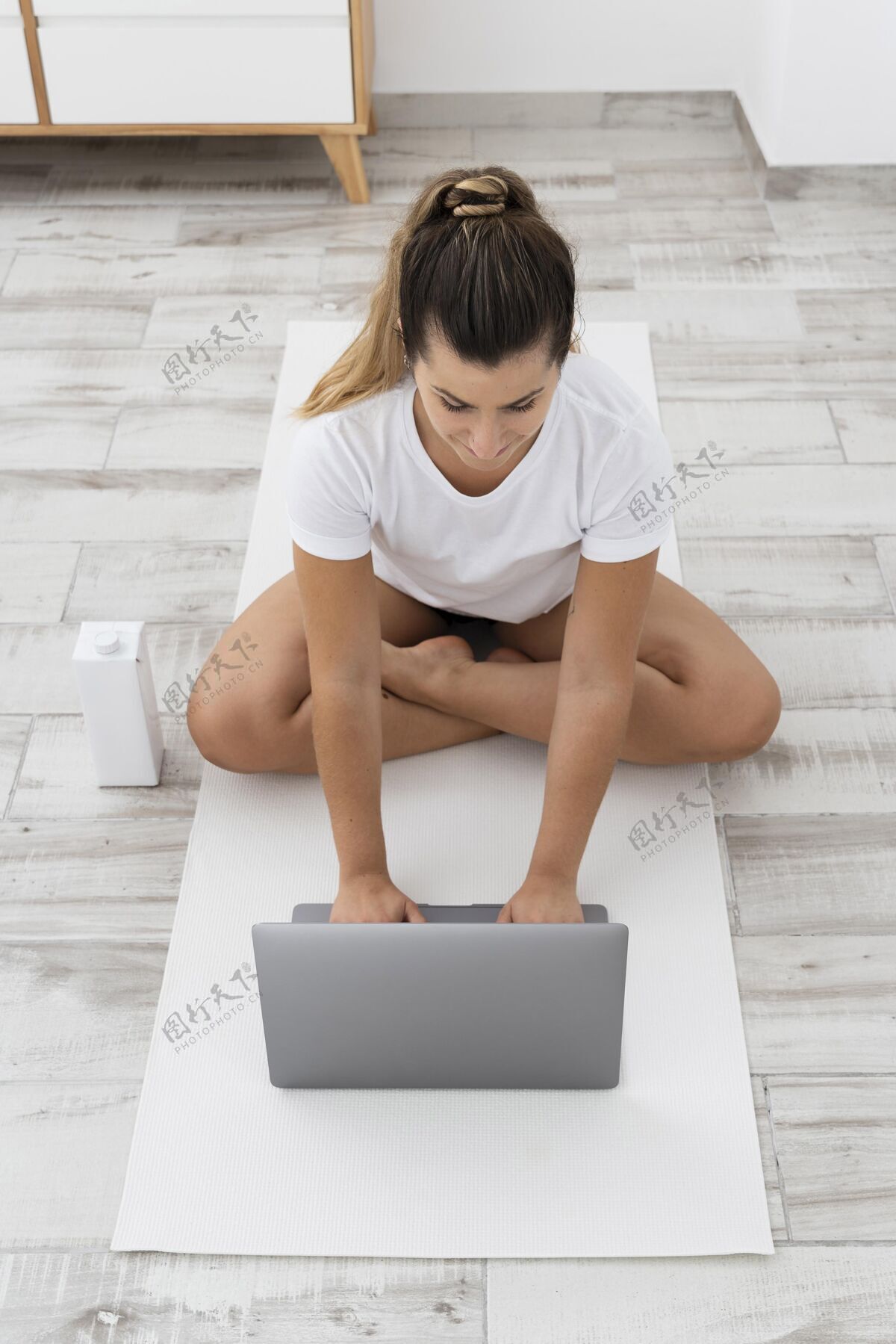 笔记本电脑运动型女人在家做瑜伽地板放松瑜伽
