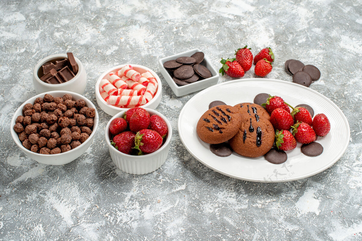 健康底视图饼干草莓和圆形巧克力放在椭圆形的盘子里 糖果草莓巧克力麦片放在灰白色的桌子上早餐糖果甜点