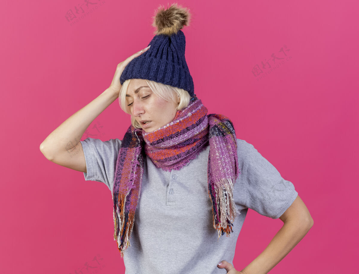 斯拉夫虚弱的年轻金发病斯拉夫妇女戴冬季帽子和围巾把手放在头上年轻疾病女人
